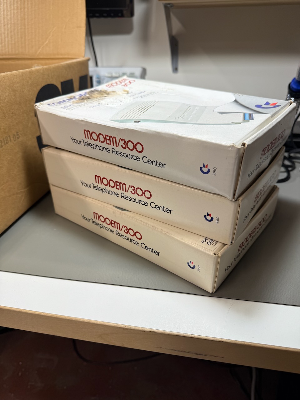 Three complete Commodore modem/300 sets, with boxes, disks, manuals, and hardware