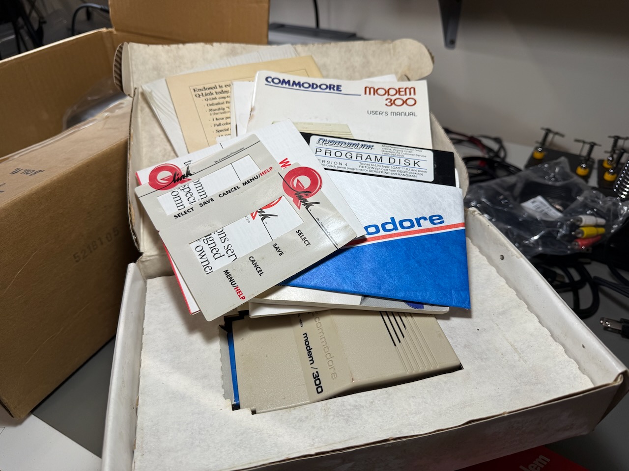 One of the Commodore modem/300 sets on display: modem, manual, disk, Q-link keyboard overlay