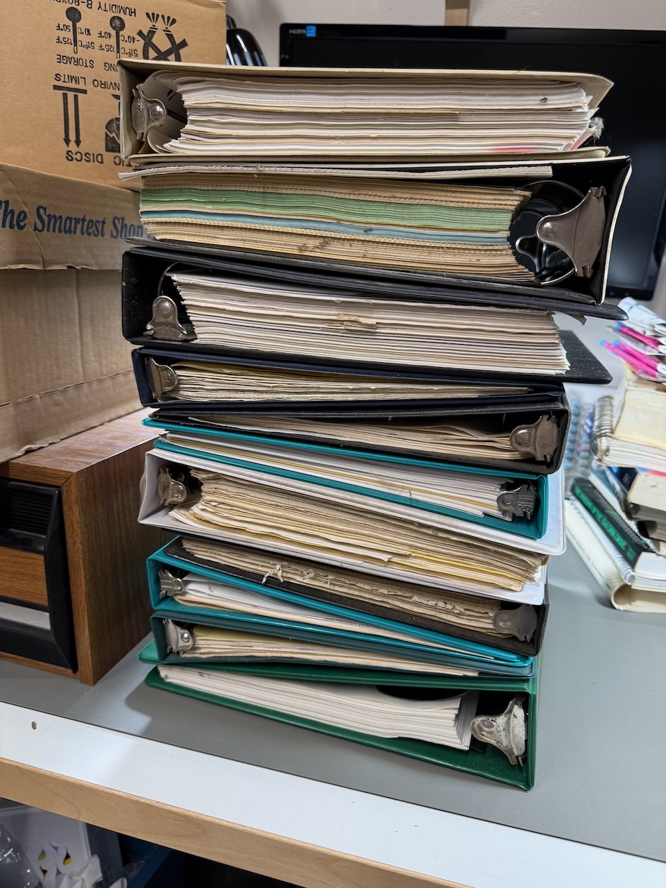 A stack of binders of printouts and notes