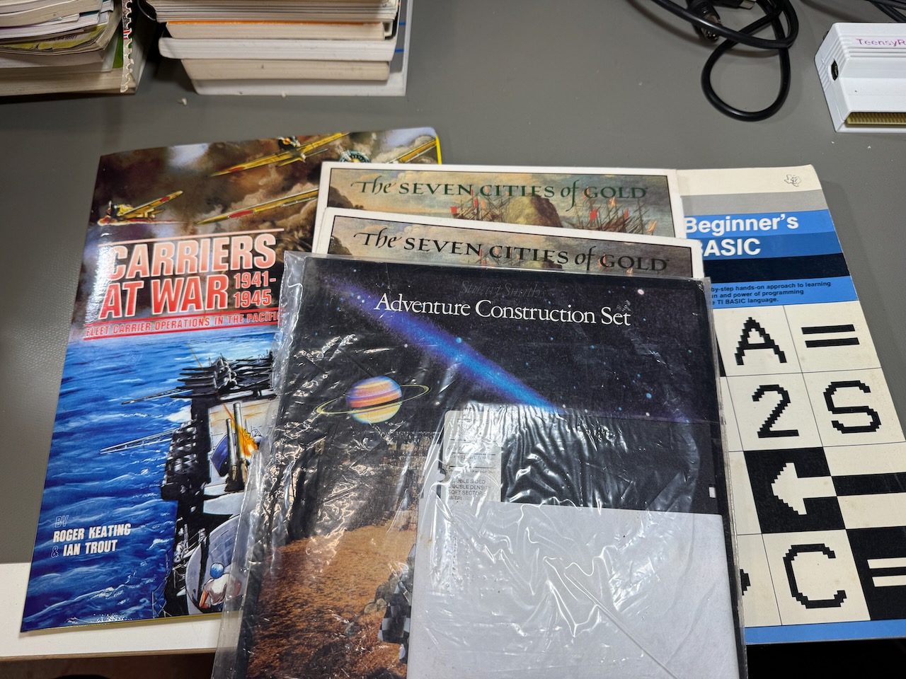 C64 software: Adventure Construction Set, two copies of Seven Cities of Gold, Carriers At War; the classic TI-99/4A Beginner's Guide to BASIC book